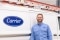 The image shows a Carrier Partner in front of a white vehicle with the Carrier logo attached to the side of the door.