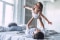 Father and daughter playing joyfully on a bed in a bright, cozy bedroom