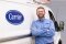 The image shows a Carrier employee in front of a Carrier van as a symbol for the maintenance service